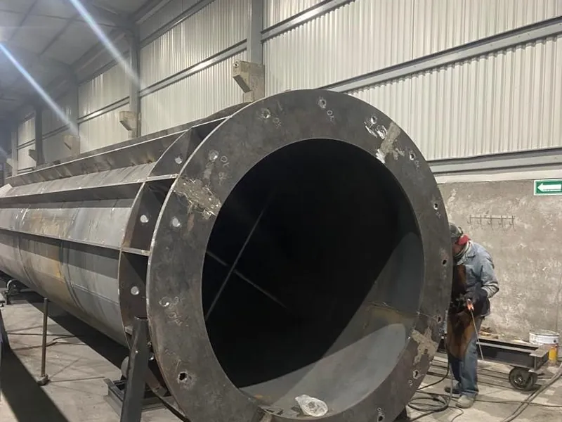 Ducto cilíndrico de gran calibre con brida, con un soldador trabajando.